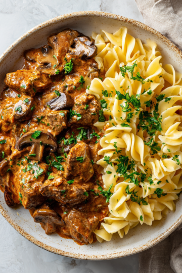 Krémový hovězí stroganov připravený v pomalém hrnci se zeleninou a kořením